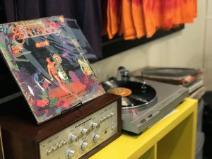 A vintage record player with a colorful album cover on top, in a retail store setting.
