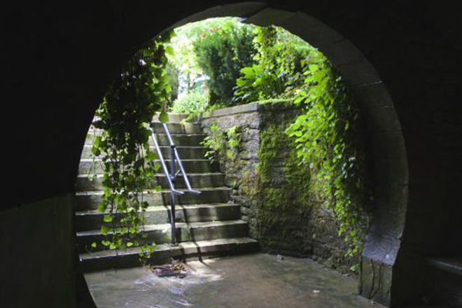 A lush green staircase under a stone archway in Eureka Springs, Arkansas.