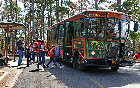 A colorful trolley bus with passengers boarding in Eureka Springs, Arkansas.