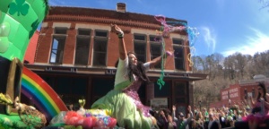 A colorful parade in Eureka Springs with performers and vibrant decorations.