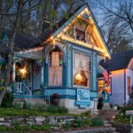 Charming blue Victorian house in Eureka Springs with festive lights and garden.
